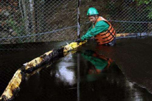 An employee places a barrier following an oil spill from a pipeline, in Chinacota, December 11, 2011