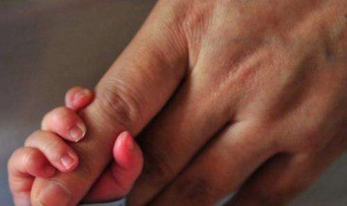 A newborn baby holds onto his mother's finger at a hospital in Beijing, on December 1, 2008