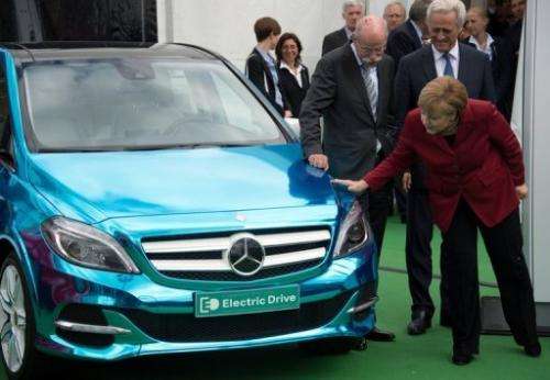 Angela Merkel (R) looks at a Mercedes E-drive electric car during the Electric Mobility conference on May 27, 2013