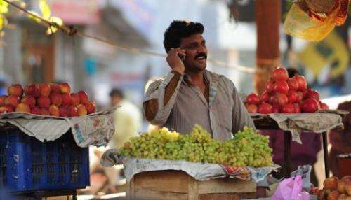 An Indian fruit vendor speaks on his mobile phone at a market in Allahabad on February 28, 2013