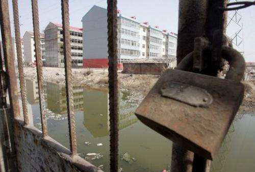 A padlock secures a gate leading to a polluted river once used for swimming, in Liukuaizhuang Village in Tianjin.