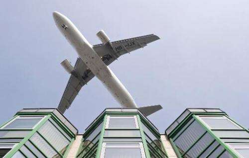 A passenger jet flies over a commercial building as it prepares to land at Berlin's Tegel airport, on March 27, 2012