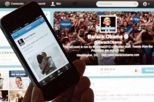 A person poses with a cell phone in front of a computer screen to check Barack Obama's tweet on November 7, 2012, Paris