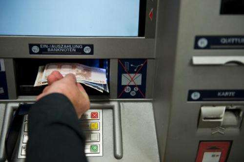A person takes out Euro banknotes from an automated teller machine at a cash point in Berlin on August 28, 2013