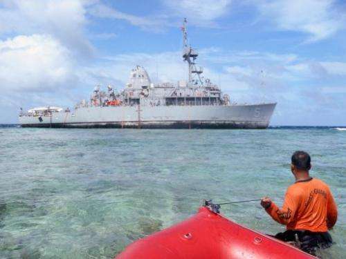 A Philippine coast guard wades towards the USS Guardian trapped on the Tubbataha coral reef, January 22, 2013