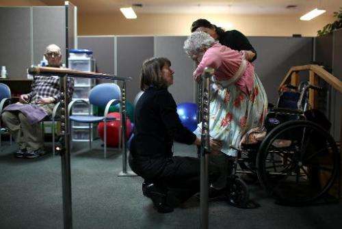 A physical therapist helps a patient stand up during a physical therapy session on February 10, 2011 in Novato, California