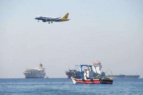 A plane flies over men from La Linea de La Concepcion fishing on August 16, 2013 near Gibraltar