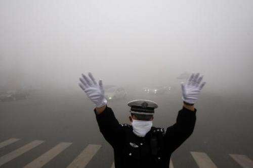 A policeman directs traffic in heavy smog in Harbin, China's Heilongjiang province, on October 21, 2013
