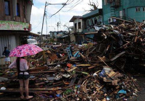 A resident stands amongst a pile of debris washed inland along a road in Tacloban, Leyte province, central Philippines on Novemb