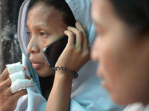 A survivor (left) talks to a relative over a borrowed mobile phone in Cebu City, central Philippines, on August 17, 2013 after a