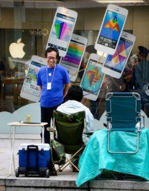 A Tokyo Apple store staff member chats with a man queuing to buy the iPhone, pictured September 11, 2013