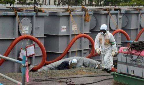 A Tokyo Electric Power worker walks next to waste water tanks at Japan's Fukushima nuclear plant on June 12, 2013
