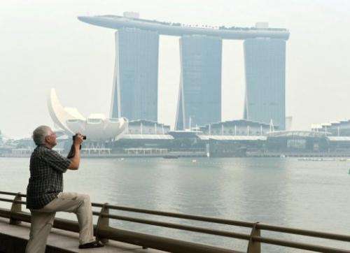 A tourist takes pictures in front of the Marina Bay Sands hotel in Singapore, on June 17, 2013