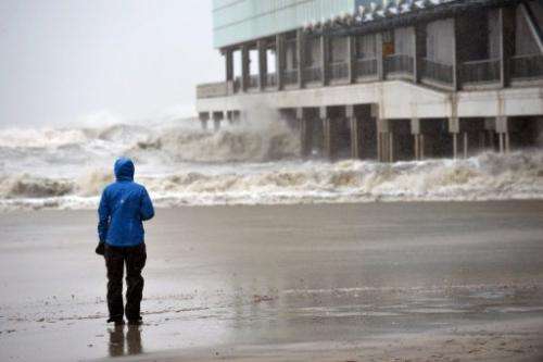 A TV reporter watches waves hit a pier before the arrival of Hurricane Sandy on October 29, 2012 in Atlantic City