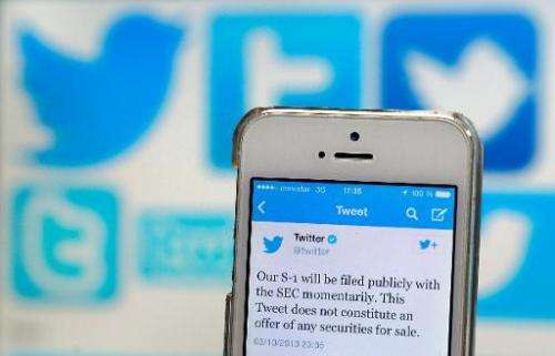 A Twitter tweet announcing the company's planned initial public offering (IPO) is pictured on a mobile telephone back-dropped by
