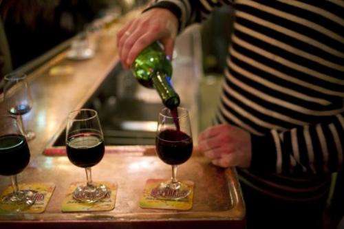 A waiter serves glasses of red wine at the counter of a bar in Paris on December 2, 2011