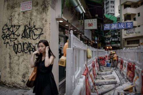 A woman blocks her ears as she walks past roadworks in Hong Kong on July 9, 2013