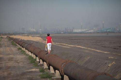 A woman standing on the banks of a 'toxic lake' surrounded by rare earth refineries near the inner Mongolian city of Baotou on A