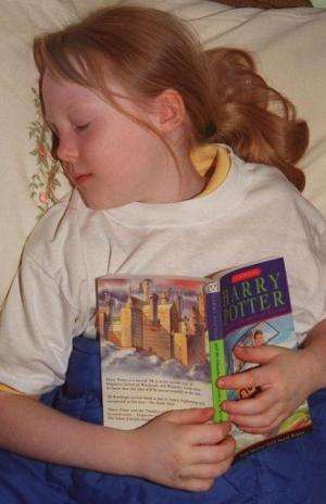 A young girl falls asleep reading a Harry Potter book in London on July 7, 2000