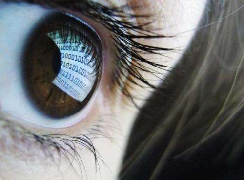 Binary code is reflected from a computer screen on a woman's eye