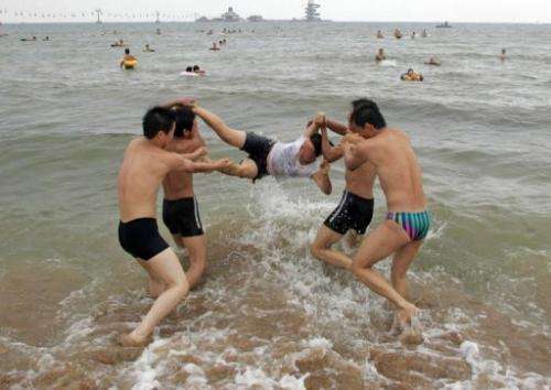 Boys toss a girl into the waters of the Bohai Sea at a beach in Qinhuangdao, on July 31, 2007