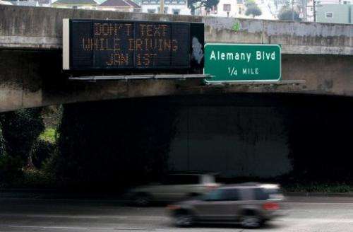 Cars drive by a sign notifying of a new texting while driving law on December 29, 2008 in San Francisco, California