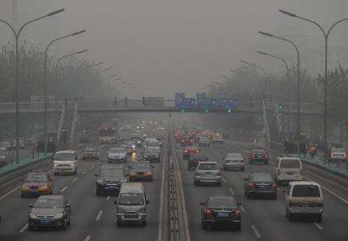 Cars travel through a haze of pollution in Beijing on December 5, 2011