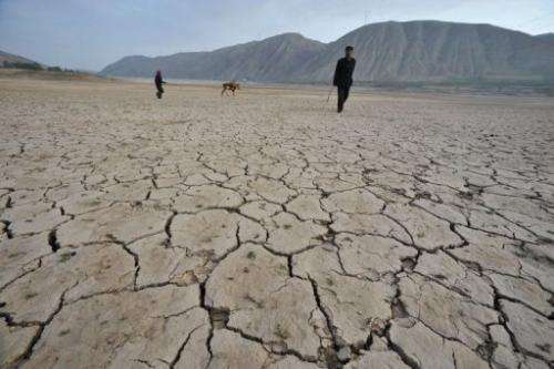 Chinese herders walk on a dried-up reservoir in Gulang, northern China's Gansu province on July 15, 2009