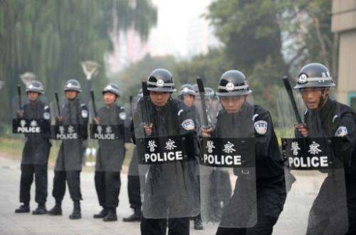 Chinese police crouch behind riot shields during a crowd control drill in Beijing on October 12, 2011