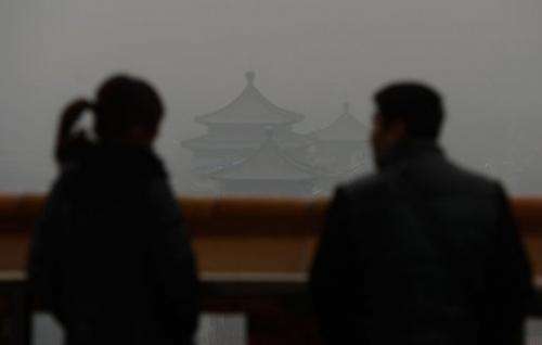 Chinese tourists look at Jingshan Park through thick smog, Beijing on January 31, 2013