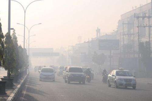 Commuters travel on a road blanketed by haze due to nearby forest fires, in Pekanbaru city, Sumatra on June 19, 2013