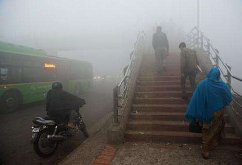 Commuters walk up a foot bridge amid smog in New Delhi on January 31, 2013