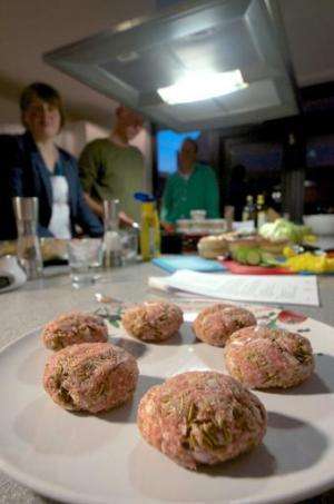 Cooking instructor Cecile Lormans (L) and her pupils look at meat balls mixed with insects, to be used for hamburgers, during an