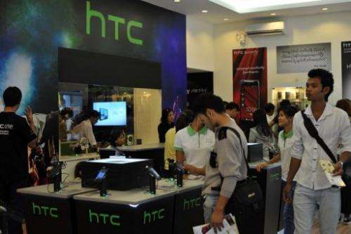 Customers look at HTC handsets on display in a HTC mobile phone shop in Yangon on January 14, 2013
