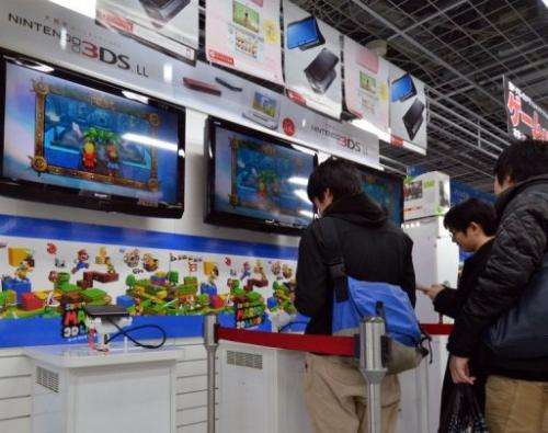 Customers play Nintendo's portable console 3DS LL at an electrics shop in Tokyo on January 30, 2013