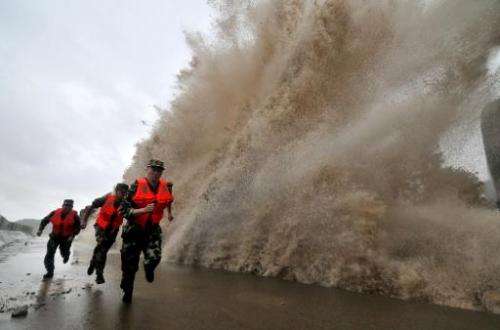 Guards run to escape a wave as Typhoon Fitow makes its landfall in Wenling, east China's Zhejiang province on October 6, 2013