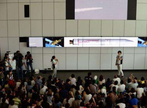 Guests watch a live transmission of the launch of Japan's new solid-fuel rocket in Kagoshima on September 14, 2013