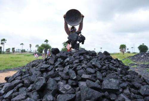 Indian labourers pile coal at a coal field on the outskirts of Hyderabad on September 5, 2012