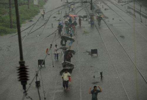 Indians walk along flooded railroad tracks during rain showers in Mumbai on July 23, 2013