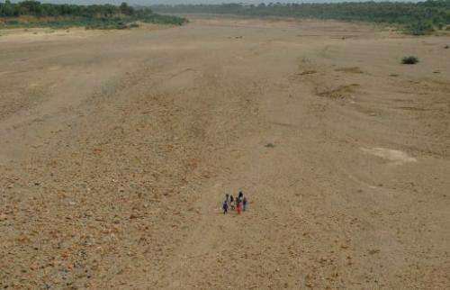 Indian villagers cross the dry bed of the Sabarmati River near Dholakuva village in Gandhinagar, on August 9, 2012