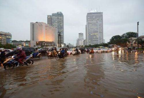 Indonesian motorists manouver through a flooded main street in Jakarta on February 6, 2013