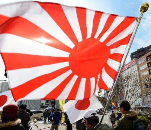 Members of a nationalist group hold a &quot;Rising Sun&quot; flag at a rally in Tokyo on February 22, 2013 over the disputed Tak