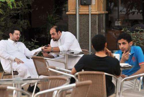 Men look at a mobile as they sit in a coffee shop in the Saudi capital Riyadh on June 17, 2013
