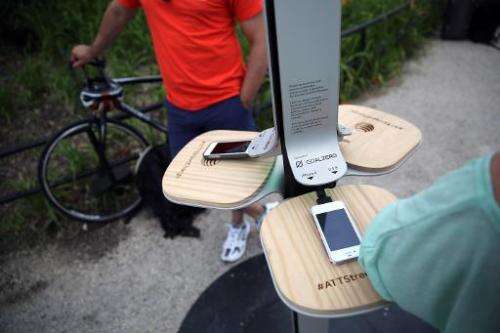 People charge their cell phones at a free solar-powered charging station set up by AT&amp;T at Brooklyn Bridge Park on June 18, 