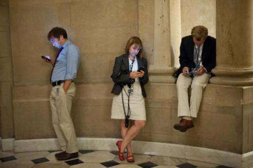 Reporters check their smartphones at the US Capitol in Washington on September 30, 2013