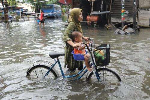 Residents wade through a flooded neighborhood to reach relief distribution centers in Jakarta on January 24, 2013