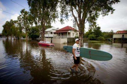 Roger Barnes rescues a friend's surfboard from a flooded home in the Brisbane suburb of Newmarket on January 28, 2013