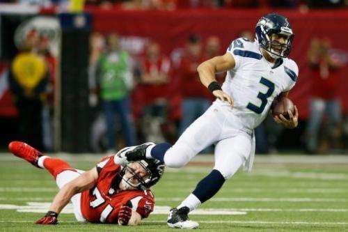 Russell Wilson of the Seattle Seahawks escapes the tackle of Kroy Biermann of the Atlanta Falcons on January 13, 2013