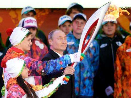 Russian President Vladimir Putin handles a torch in Moscow on October 6, 2013, to start the relay across Russia