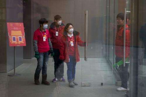 Shop assistants wear face masks as they welcome customers at a store in Beijing, January 29, 2013